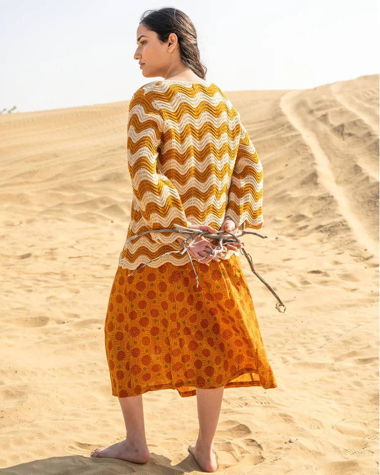 A woman wearing a patterned skirt and knit sweater from Gudrun Sjödén. 