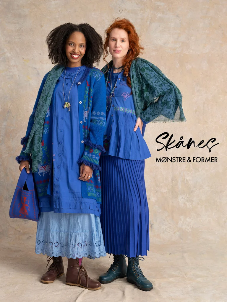 Two women standing closely together wearing layers of clothing in shades of blue from Gudrun Sjödén.