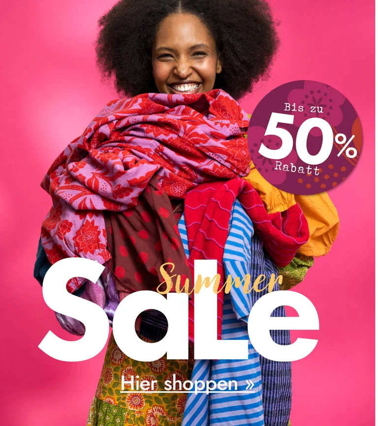 A woman with her arms full of colourful clothes from Gudrun Sjödén.
