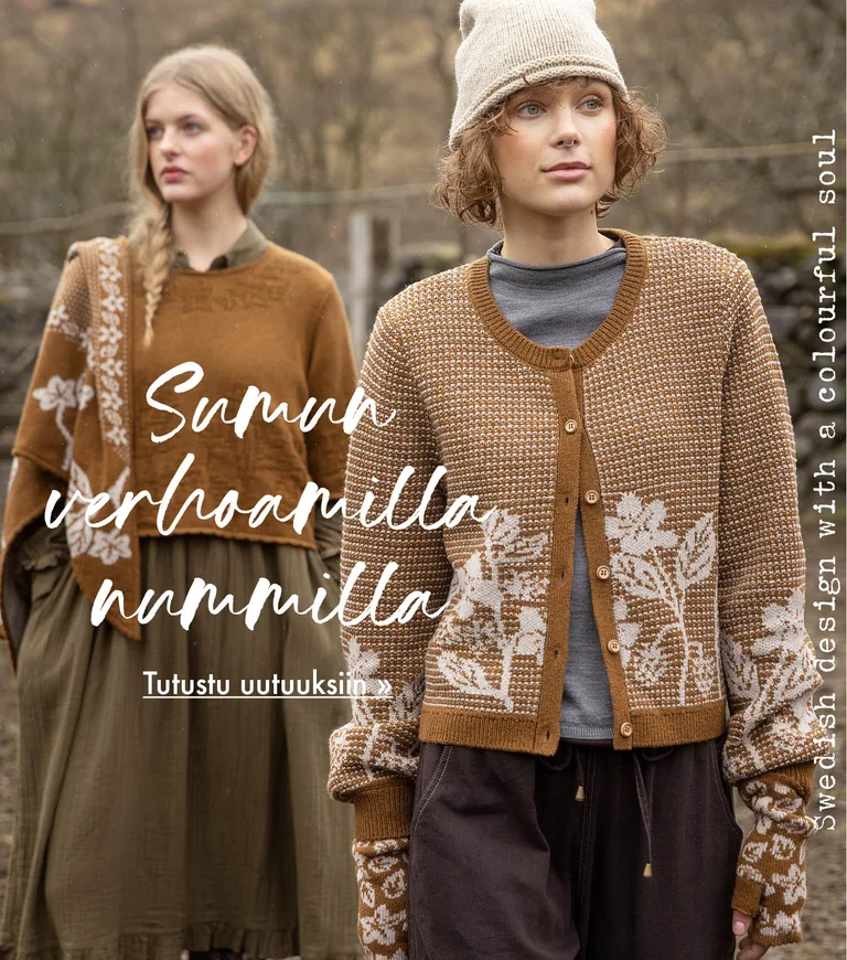 Two women standing next to each other wearing clothes in earthy hues from Gudrun Sjödén. Sheep and a stone wall are visible in the background.