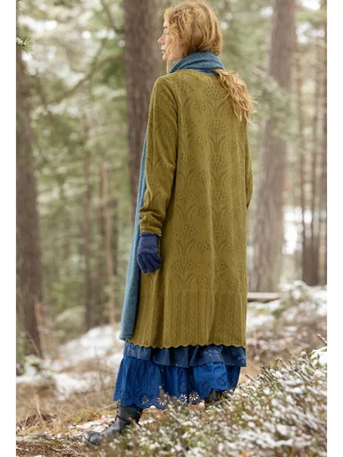 Eine Frau in einem grünen Strickkleid von Gudrun Sjödén. 