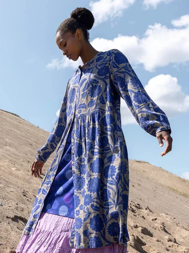 A woman sitting down wearing colourful clothes from Gudrun Sjödén. 