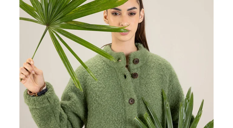 A closeup of a woman wearing a green bouclé jacket in wool from Gudrun Sjödén.