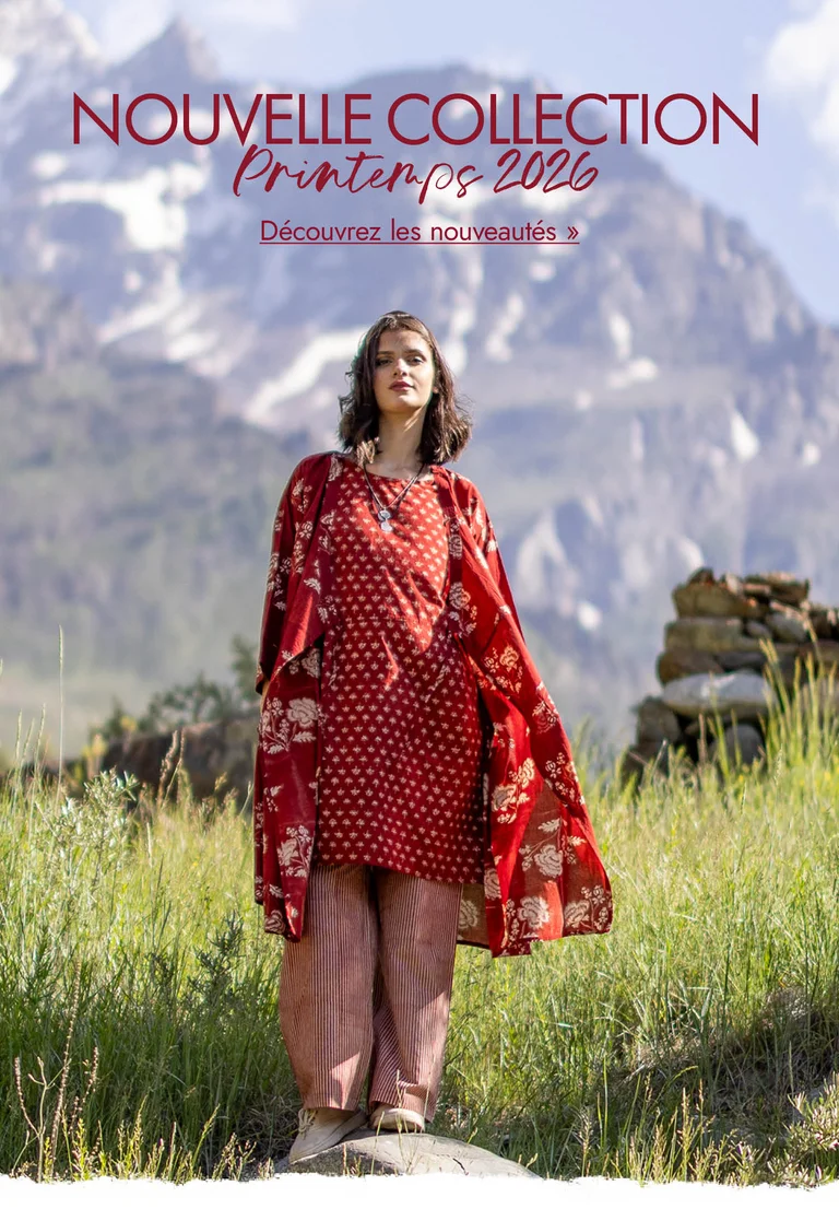 Une femme se tenant dans un paysage montagneux et portant des vêtements rouges tissés signés Gudrun Sjödén.