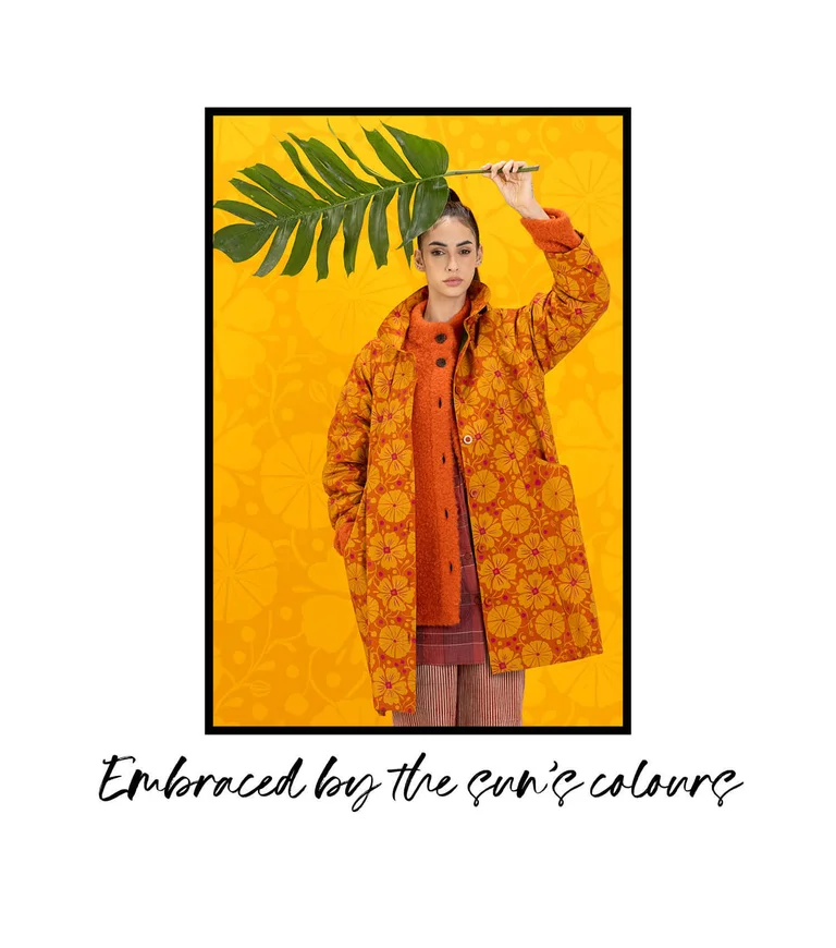 A woman wearing a patterned orange coat from Gudrun Sjödén.