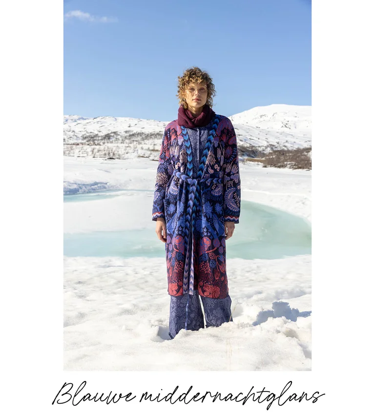 Een vrouw die in een sneeuwlandschap staat en laagjes kleding draagt uit de kerstcollectie 2025 van Gudrun Sjödén.