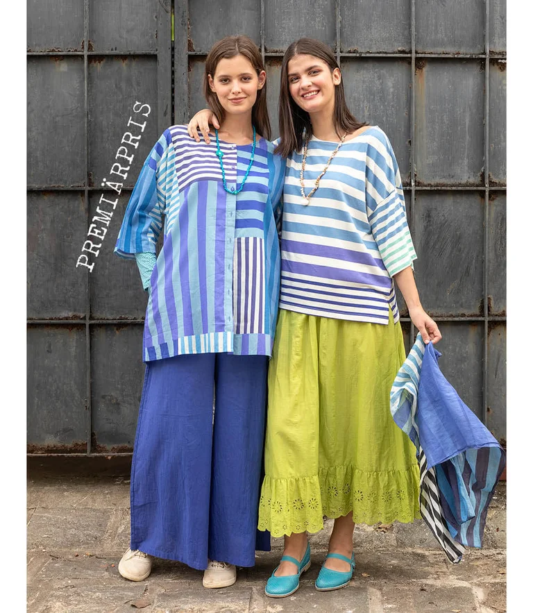 Two women wearing striped clothes from Gudrun Sjödén. One woman is holding a matching scarf in her hand.