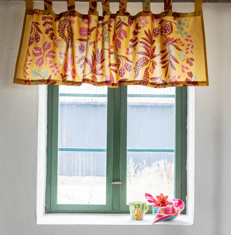 Ein Fenster mit einer gemusterten Bistrogardine von Gudrun Sjödén.