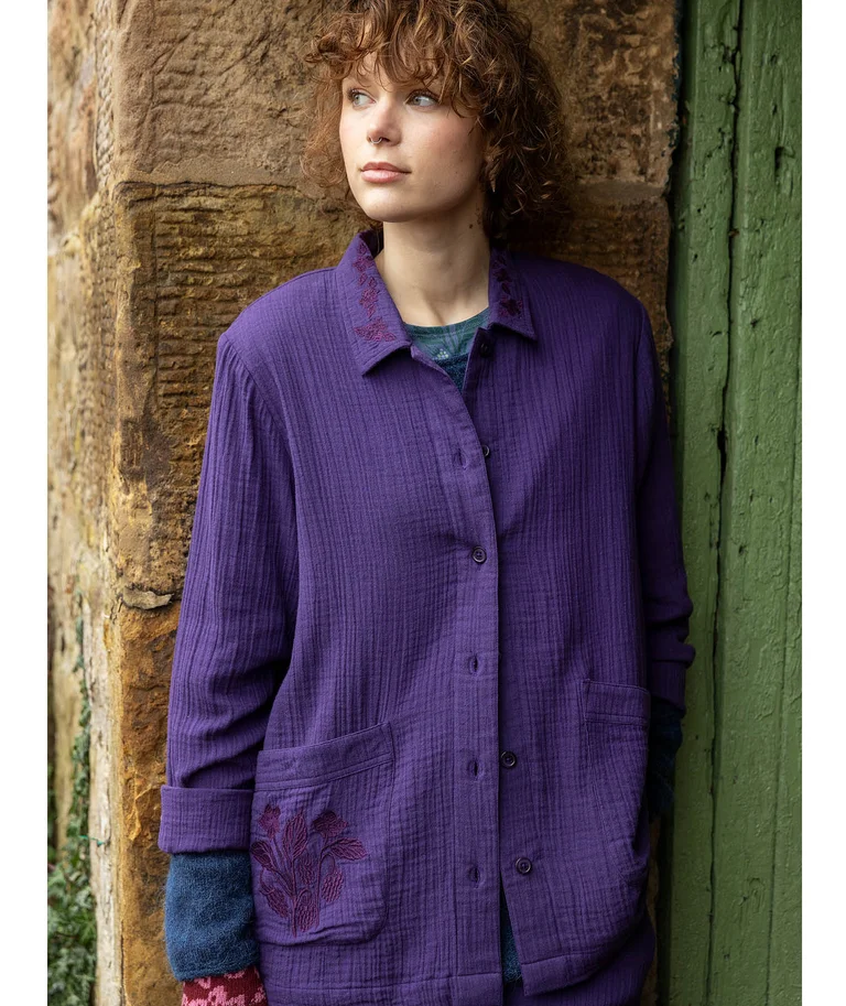 A woman wearing a solid-colored jacket in purple from Gudrun Sjödén.