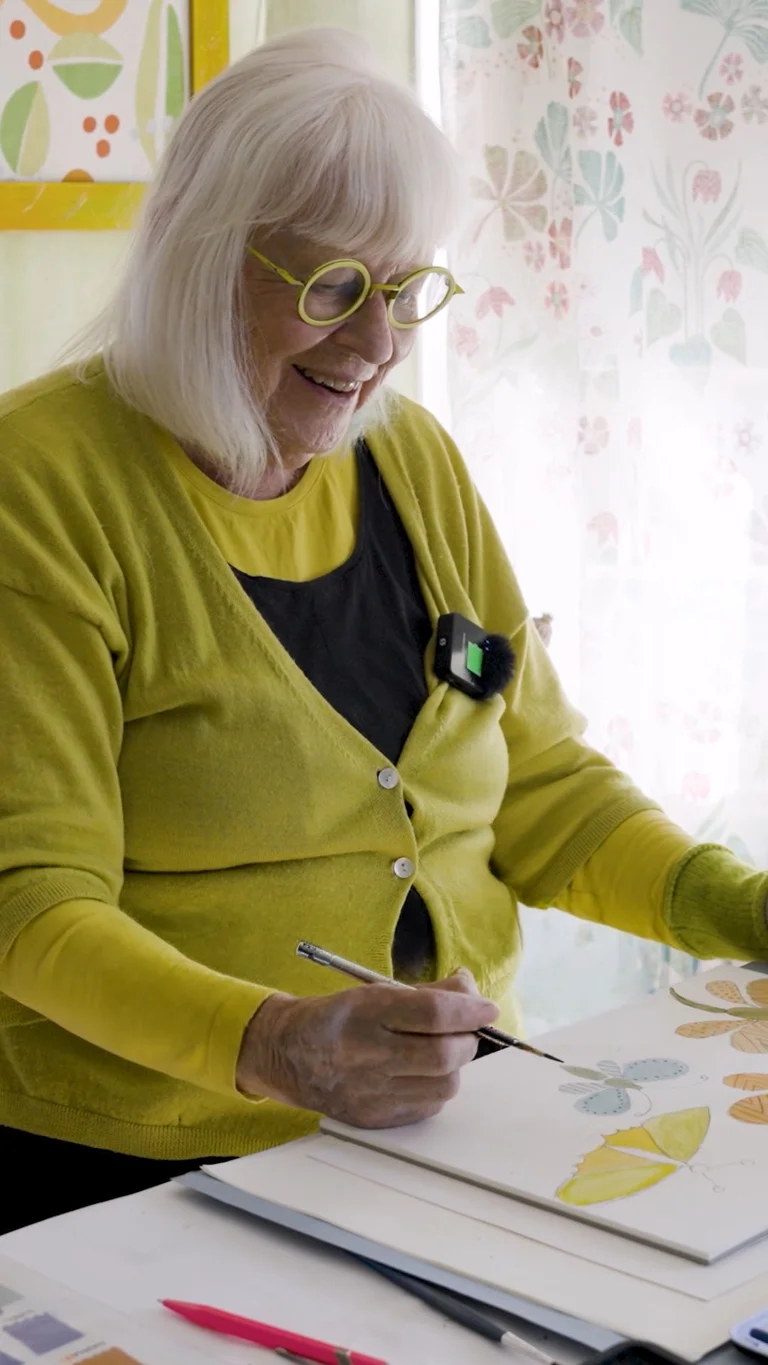 En video med Gudrun där hon sitter i sin ateljé och målar fjärilar med akvarellfärg.