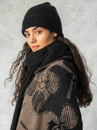 A woman wearing a black beanie and scarf from Gudrun Sjödén. 