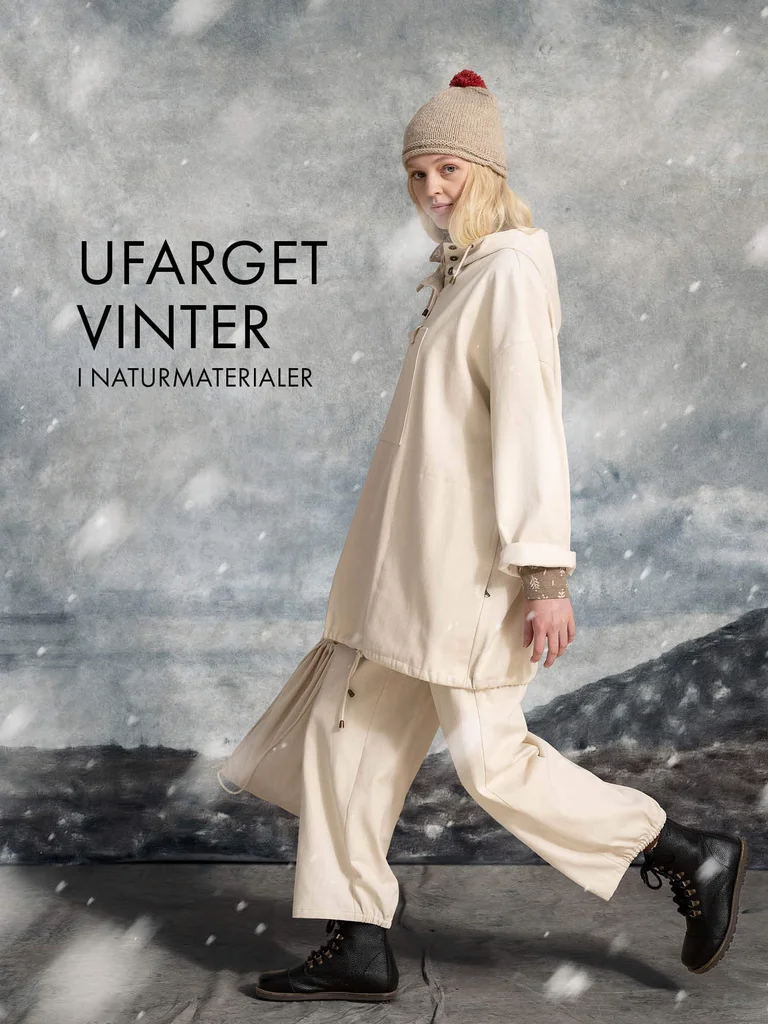 A woman walking while snow falls, wearing a knit hat, a white anorak and a pair of white pants from Gudrun Sjödén.