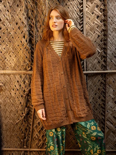A woman wearing a brown knitted cardigan from Gudrun Sjödén. 