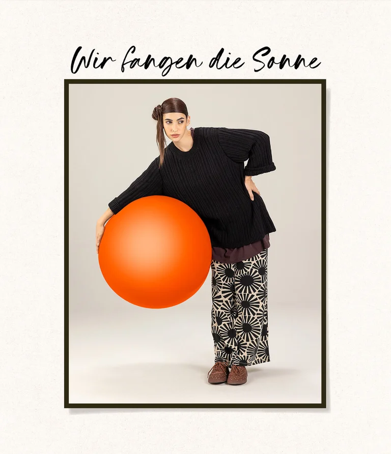 A woman wearing black and white clothing from Gudrun Sjödén, holding a large red ball. 