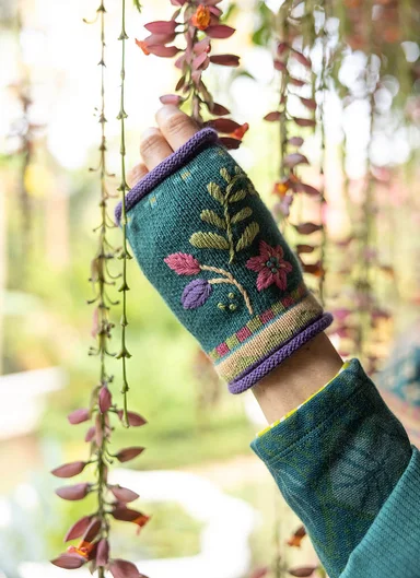 A woman wearing knitted fingerless gloves from Gudrun Sjödén. 