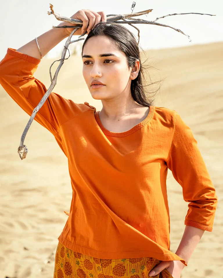 A woman wearing an orange top from Gudrun Sjödén.