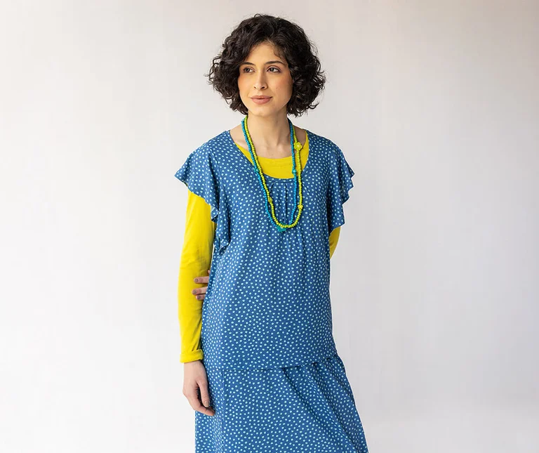 Eine Frau im gepunkteten blauen Jerseyshirt und passendem Rock von Gudrun Sjödén.