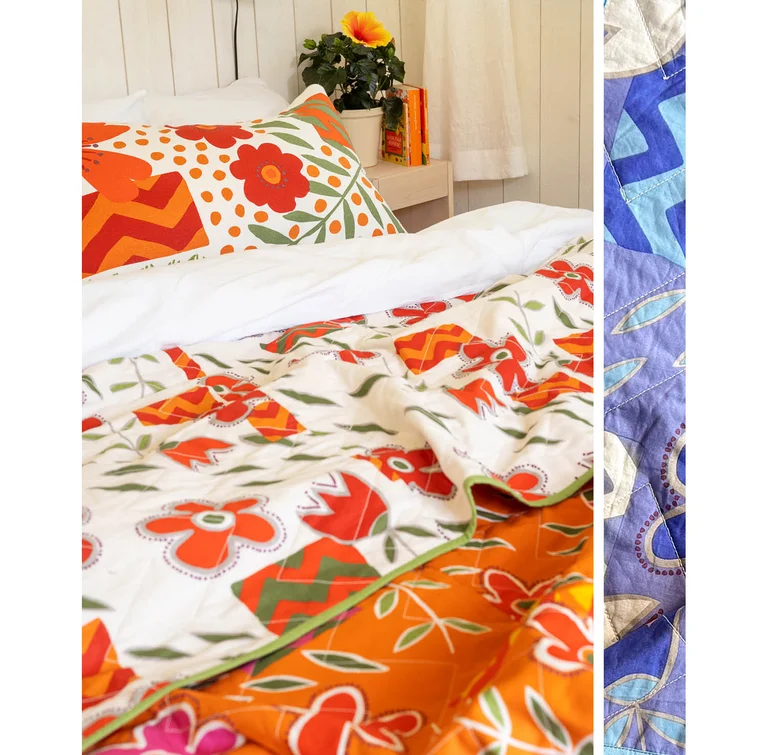 A quilted bedspread from Gudrun Sjödén with orange and red flowers on a made bed, with a floral cushion cover from Gudrun Sjödén. On the right, a close-up of a quilted cloth with a blue and purple pattern.