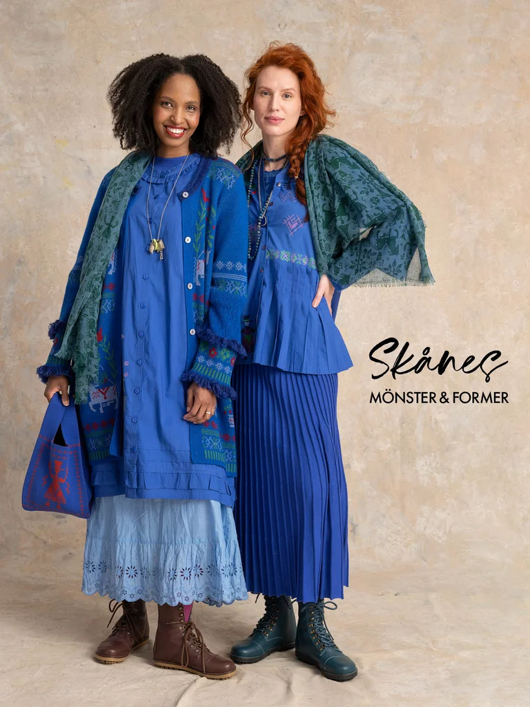 Two women standing closely together wearing layers of clothing in shades of blue from Gudrun Sjödén.