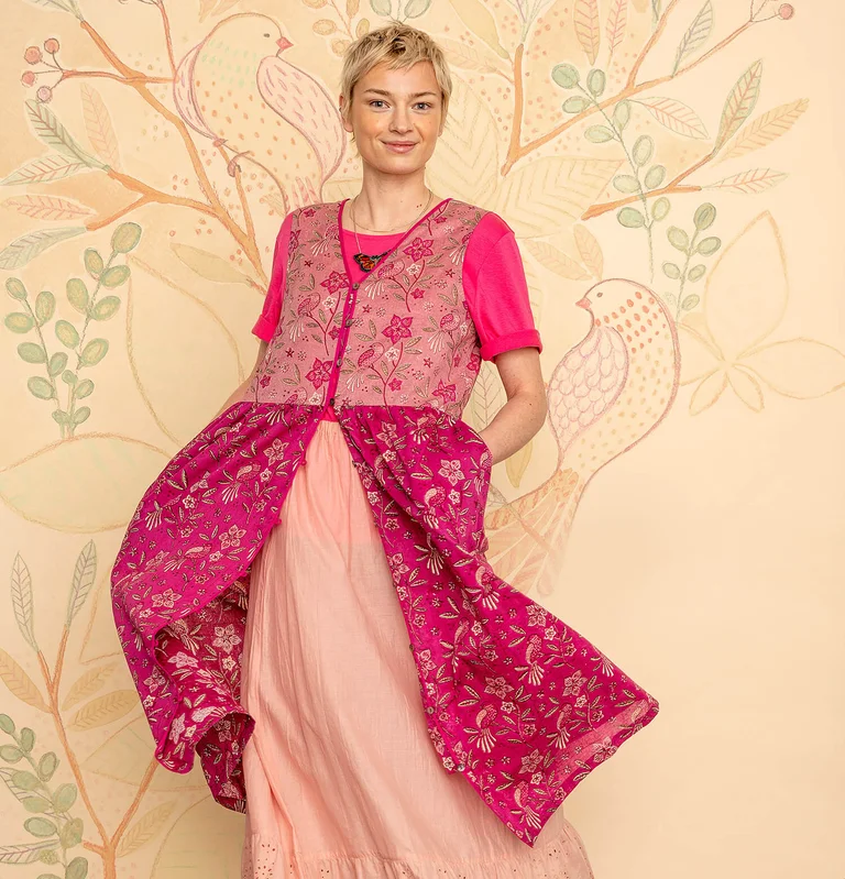A woman wearing a pink floral dress from Gudrun Sjödén. 