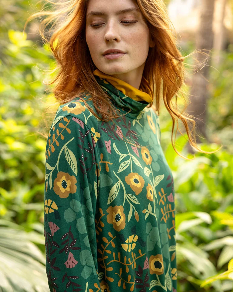 A woman wearing a patterned green tunic from Gudrun Sjödén.