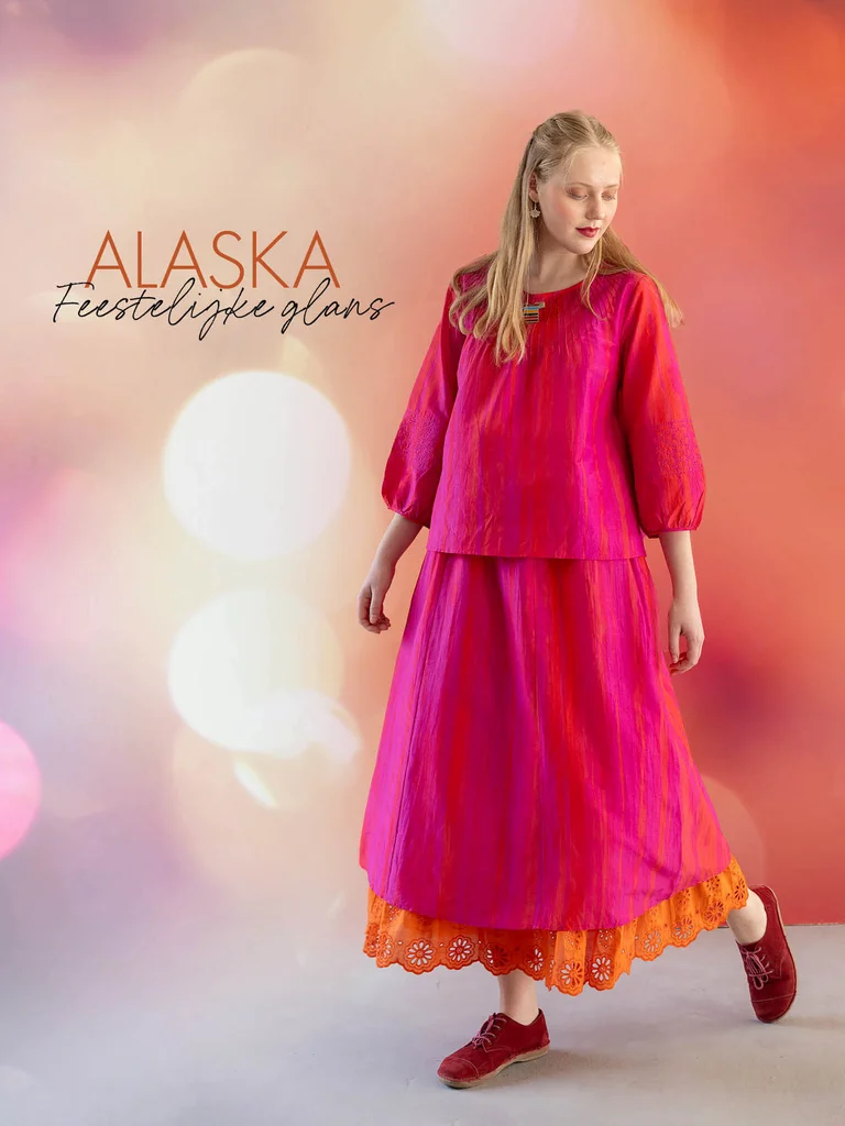 Een vrouw met een roze, glanzende top en een bijpassende rok uit de kerstcollectie van 2025 van Gudrun Sjödén.