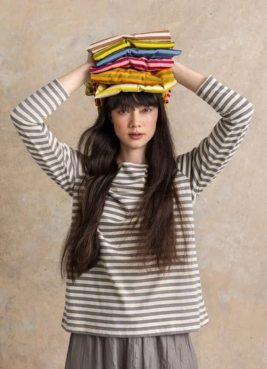 A woman wearing a grey and white striped jersey sweater from Gudrun Sjödén.
