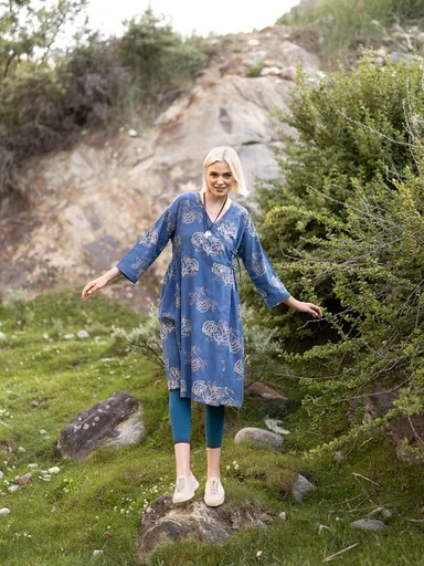 A close-up of the upper body of a woman wearing a striped woven garment from Gudrun Sjödén.