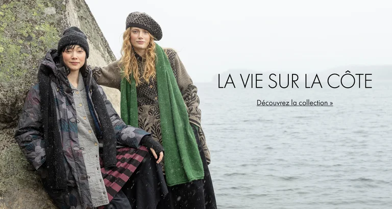 Deux femmes posant contre un rocher près de l'eau, portant des vêtements et des accessoires provenant de la collection d'hiver 2025 de Gudrun Sjödén. 