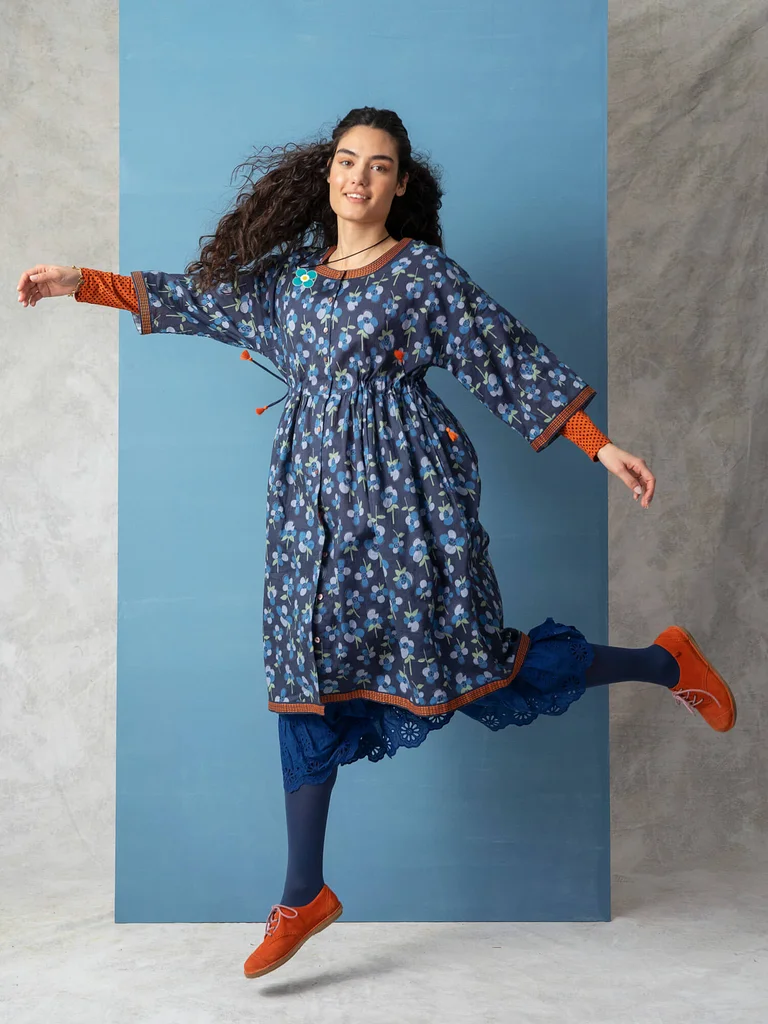 A woman wearing a blue floral dress from Gudrun Sjödén.  