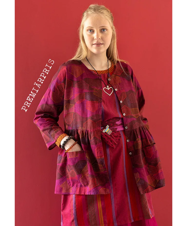 A woman wearing a button-up pink-red blouse from Gudrun Sjödén’s 2025 Christmas collection.