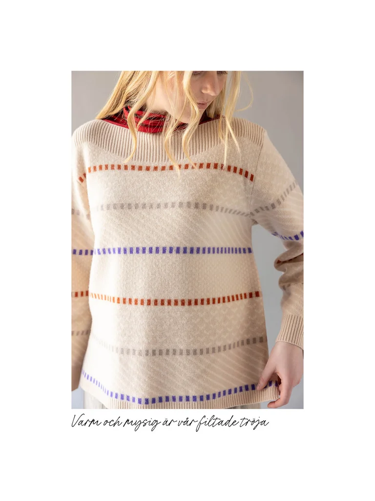 A close-up of a woman wearing a striped, white sweater from Gudrun Sjödén’s 2025 Christmas collection.