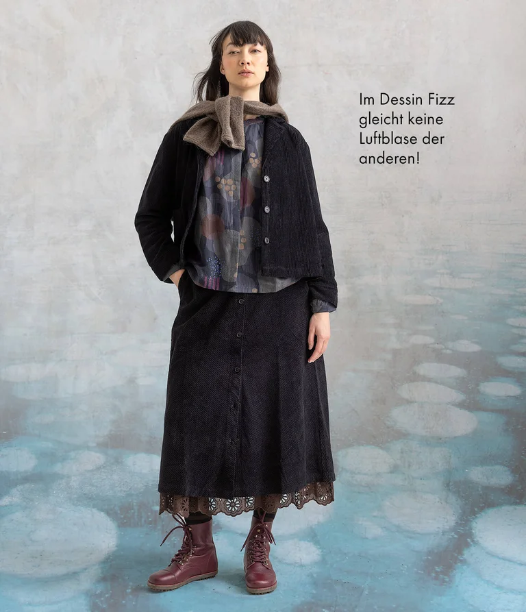 Eine Frau in Cordjacke und -rock von Gudrun Sjödén.
