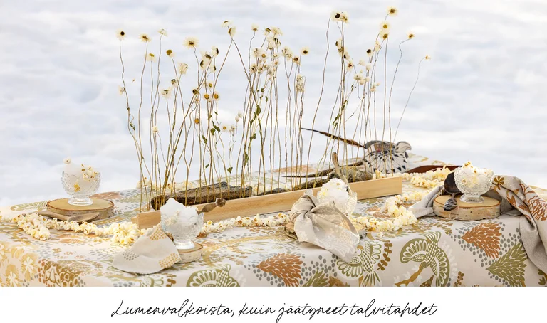 A table in the snow laid with home textiles from Gudrun Sjödén’s 2025 Christmas Home collection.