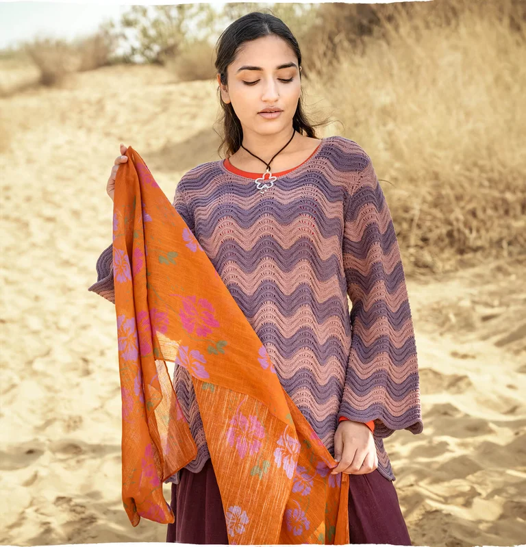 A woman wearing a patterned knit sweater and scarf from Gudrun Sjödén. 