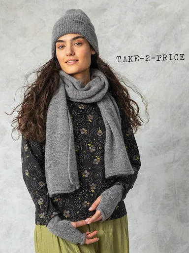 A woman wearing a grey beanie, scarf and fingerless gloves from Gudrun Sjödén.
