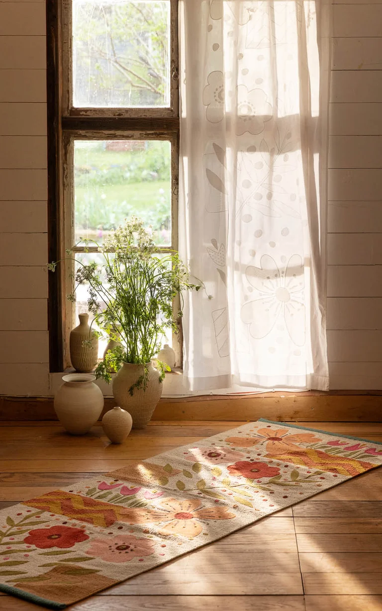 A white curtain from Gudrun Sjödén with embroidered flowers in a window.