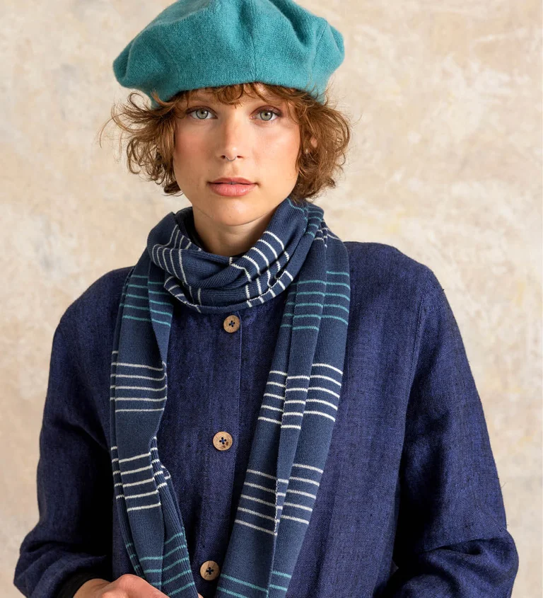 A woman wearing a beret and a knitted striped scarf from Gudrun Sjödén.