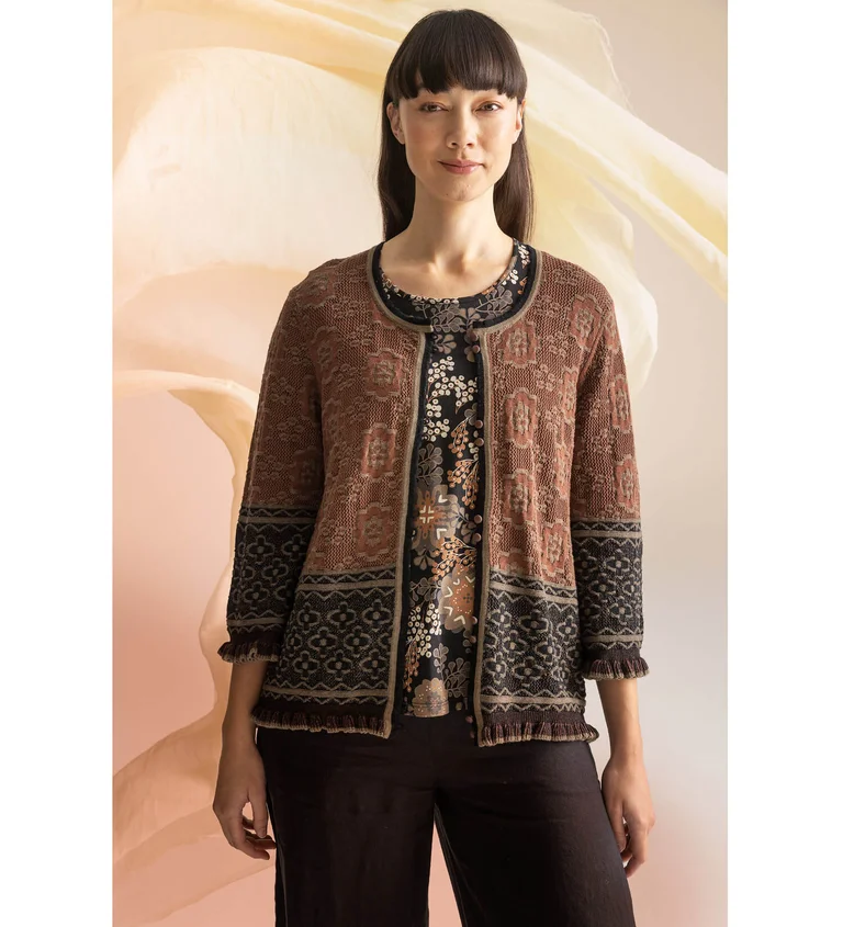 A woman wearing a patterned top and cardigan from Gudrun Sjödén.