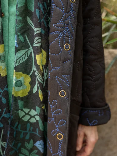 A woman wearing a jersey jacket and patterned scarf from Gudrun Sjödén.