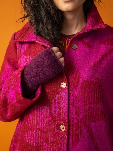 A woman wearing a patterned coat and reddish purple fingerless gloves from Gudrun Sjödén. 