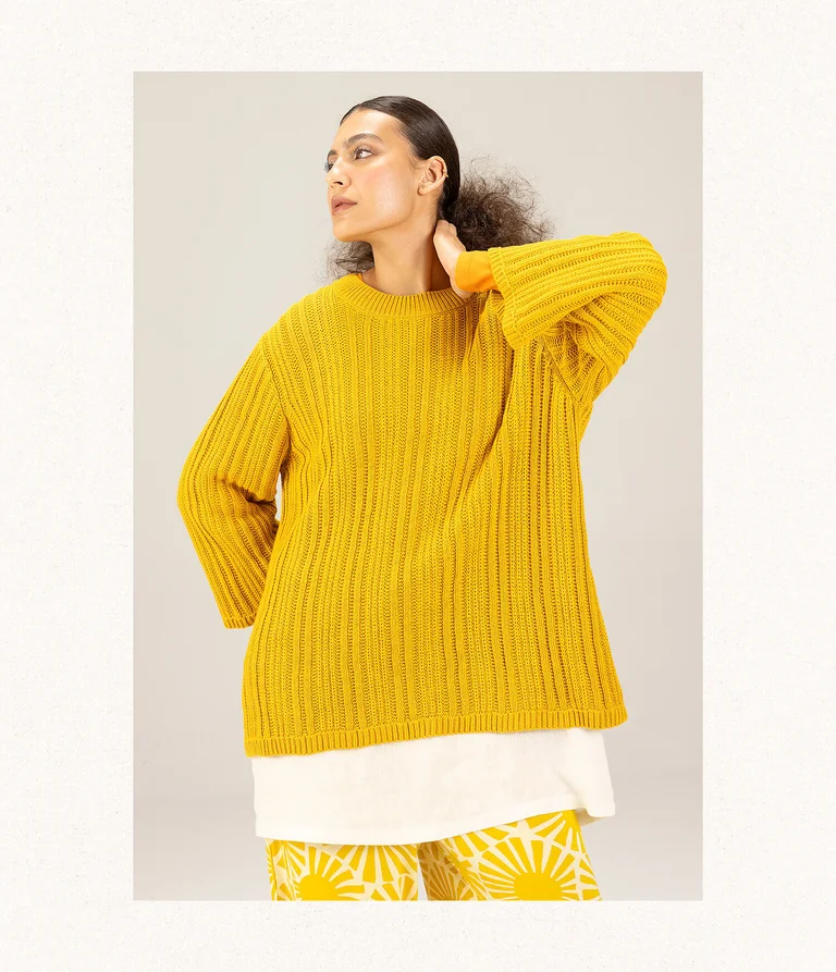 A woman posing in a yellow knit sweater from Gudrun Sjödén. 