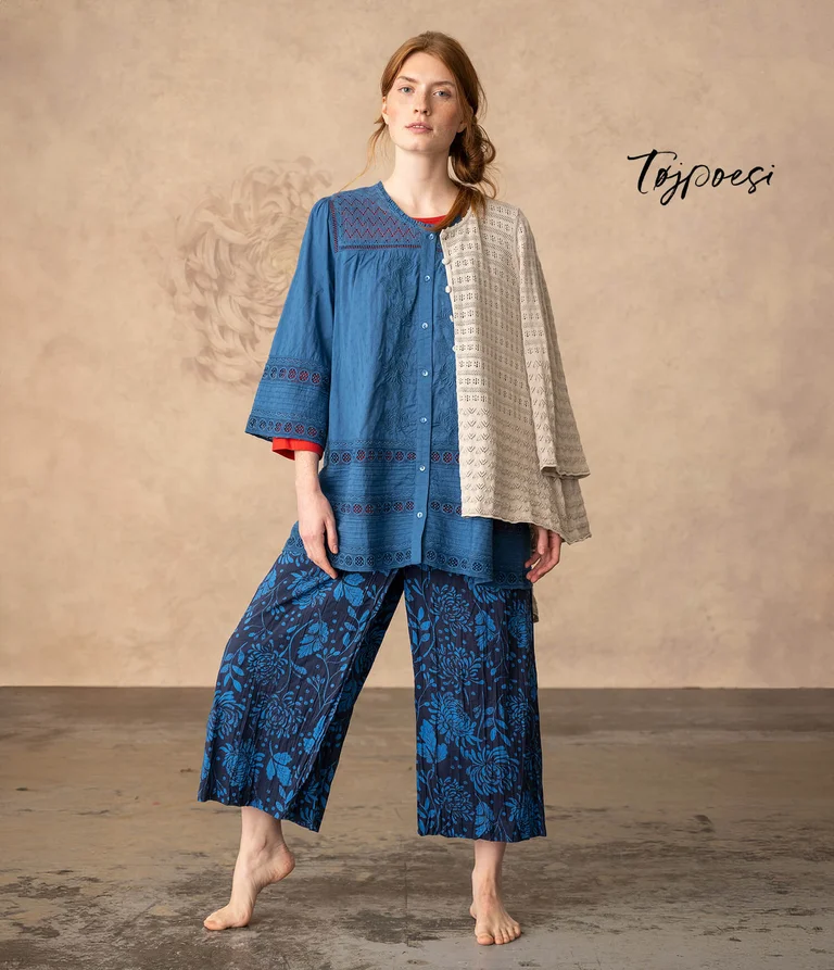 A woman wearing a blue blouse and patterned blue pants from Gudrun Sjödén.