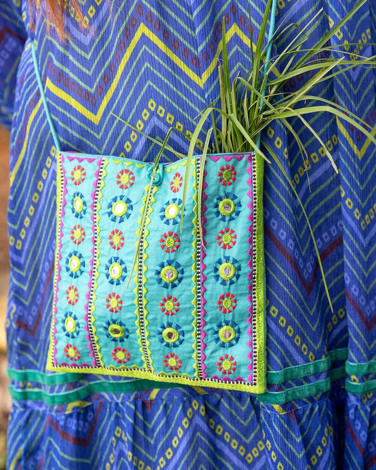 A closeup of a blue-green embroidered bag from Gudrun Sjödén. 
