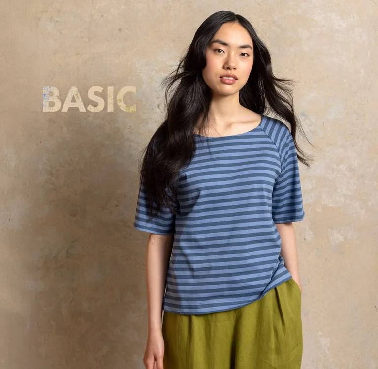 A woman in a studio wearing a blue, striped, short-sleeve top from Gudrun Sjödén’s Essentials collection.