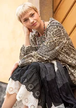 Frau trägt Naturmode von Gudrun Sjödén - eine beige Baumwolltunika und braunem Rosenmuster und dazu einen schwarzen und weißen Unterrock.