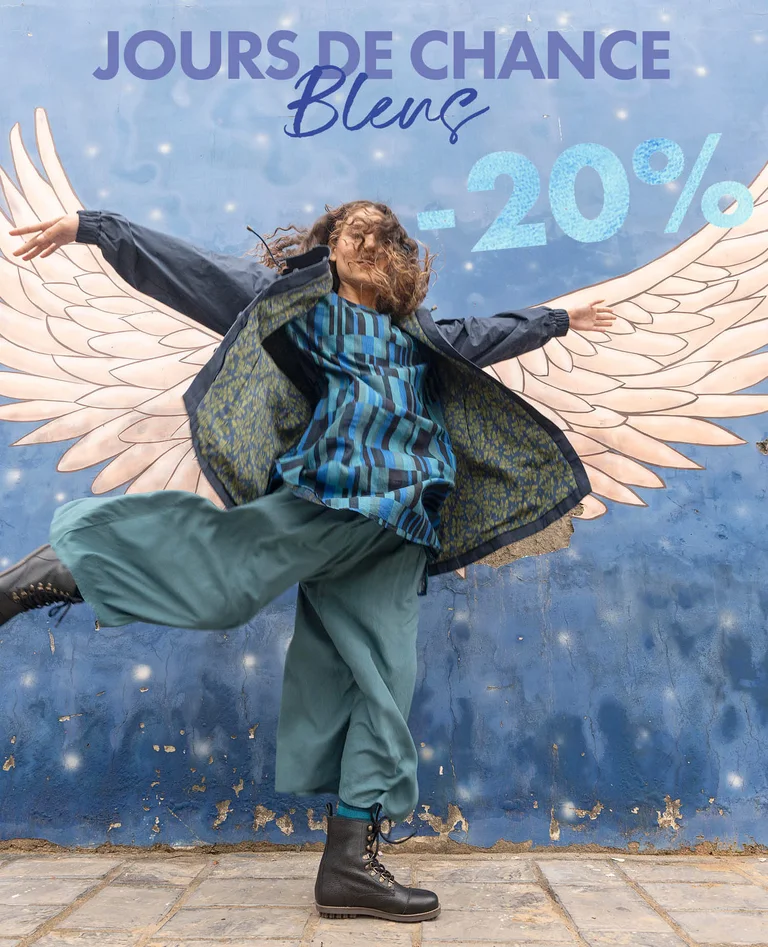 Une femme portant des superpositions de vêtements bleus signés Gudrun Sjödén. 