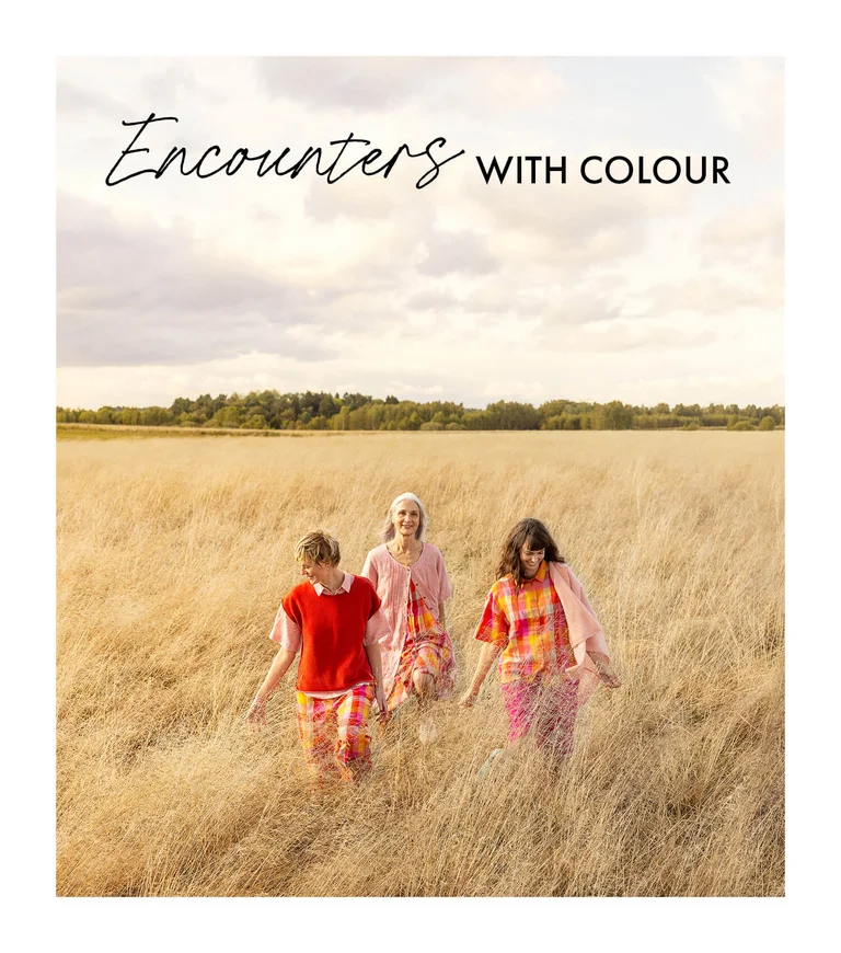 Three women wearing colourful creations from Gudrun Sjödén.