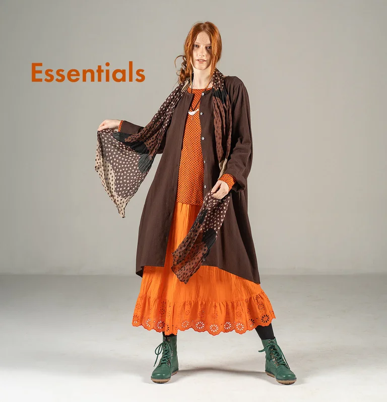 A woman wearing layered brown-orange tone clothing from Gudrun Sjödén.  