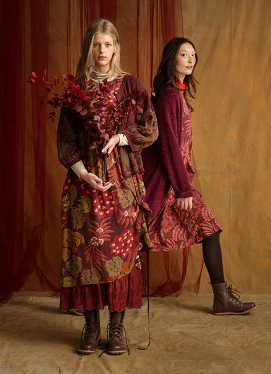 Two women wearing layers of clothes in shades of burgundy from Gudrun Sjödén.